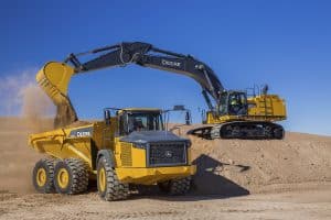 John Deere excavator emptying construction debris into articulated dump truck. Illustrates the importance of the RE568454 John Deere DPF and how it can be replaced by Roadwarrior’s D2012-SA.