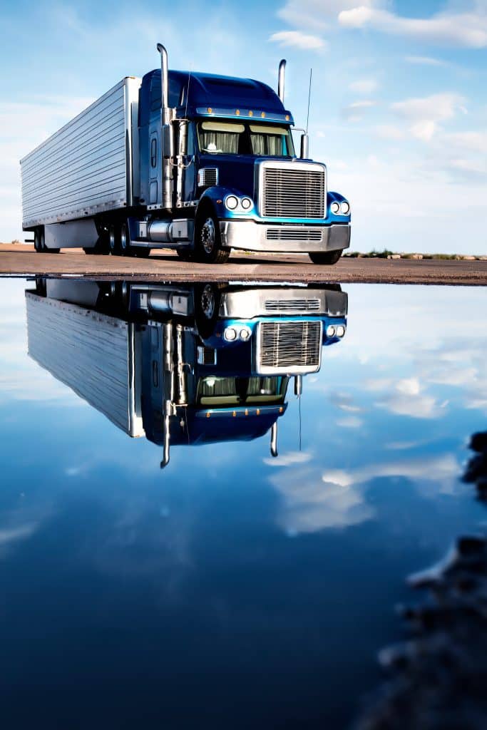 Image of a blue truck reflected in a puddle, to illustrate the benefits of the Roadwarrior NOx sensor offering. 